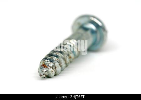 Nahaufnahme der Stillzeit, die die leicht rostige Spitze einer einzelnen silberfarbenen Schraube zeigt, die vor einem weißen Hintergrund mit geringer Schärfentiefe isoliert ist. Stockfoto