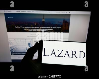 Person, die das Smartphone mit dem Logo des US-Finanzdienstleisters Lazard Ltd. Auf dem Bildschirm vor der Website hält. Konzentrieren Sie sich auf die Telefonanzeige. Stockfoto