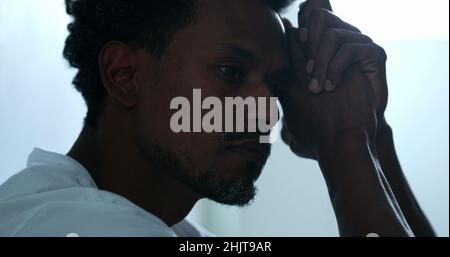 Deprimierter Mann, der auf dem Boden sitzt. Traurige unglückliche Person, die seine Stirn hält und an einer psychischen Erkrankung leidet Stockfoto