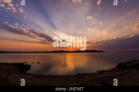 Bunte Sonnenstrahlen nach Sonnenuntergang in San Ignacio, Misiones, Argentinien, mit kleinen Bergen am Horizont Stockfoto