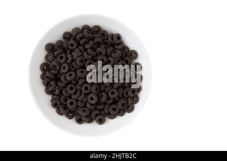 Haufen schwarzer Getreideringe isoliert auf weißem Hintergrund, leckere und nützliche Ringe Frühstückszerealien in Schüssel, Draufsicht Stockfoto