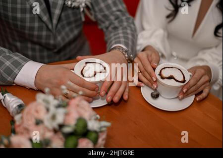 Mann und Frau halten weiße Kaffeebecher im Café. Latte Art Stockfoto