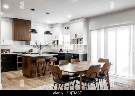 Moderne Küche und Esszimmer im mittleren Jahrhundert mit schwarzen Schränken, weißen Schränken, weißen Quarz- und Walnussakzenten Stockfoto