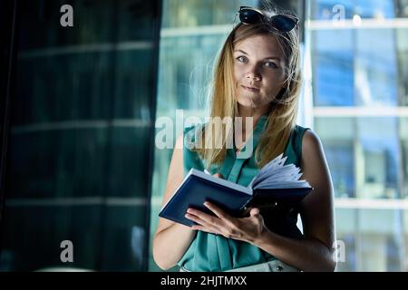 Frau im Geschäftsanzug schreibt im Notizbuch draußen. Stockfoto