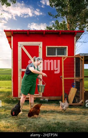Eine Frau, die Hühner auf einem Bauernhof füttert Stockfoto