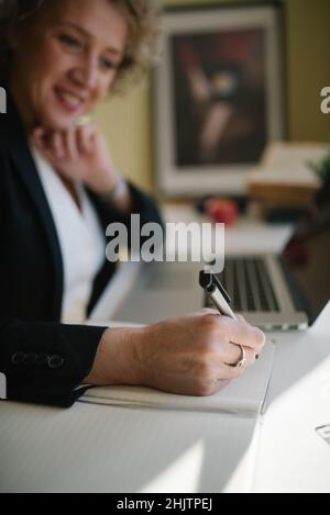 Lächelnde Geschäftsfrau, die aus der Nähe Notizen schreibt. Stockfoto