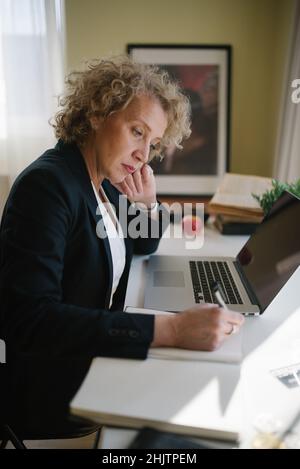 Frau mittleren Alters, die zu Hause arbeitet. Stockfoto