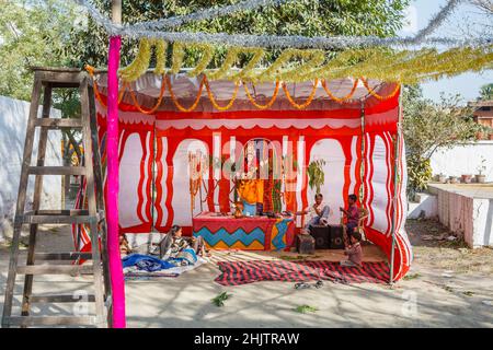 Ein farbenfroher Hindu-Schrein am Straßenrand mit einer Göttensstatue und Ringelblumen in Varanasi, einer Stadt am Fluss Ganges in Uttar Pradesh, Nordindien Stockfoto