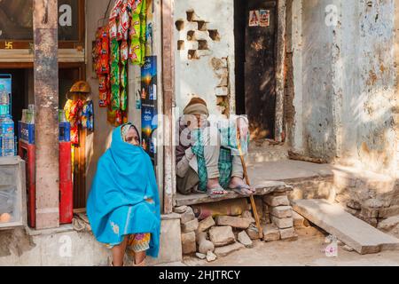 Ein alter Mann und eine alte Frau sitzen in einem Ladeneingang in Varanasi (früher Banaras oder Benares), einer Stadt am Fluss Ganges in Uttar Pradesh, Nordindien Stockfoto