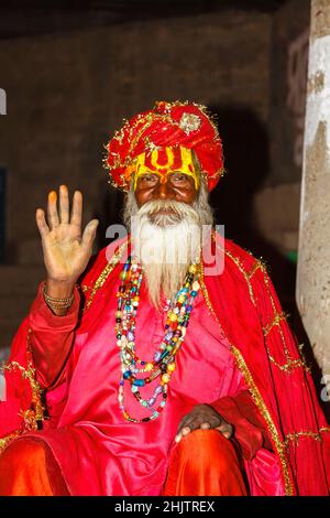 Hinduistischer Lebensstil: Porträt eines typischen Sadhu oder heiligen Mannes mit erhobener Hand zum Segen in Varanasi , einer Stadt am Fluss Ganges in Uttar Pradesh, Indien Stockfoto