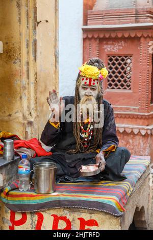 Hinduistischer Lebensstil: Porträt eines typischen Sadhu oder heiligen Mannes mit erhobener Hand zum Segen in Varanasi , einer Stadt am Fluss Ganges in Uttar Pradesh, Indien Stockfoto