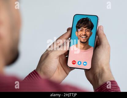 Mann, der mit einem Freund ein Smartphone hält, zwei araber, die einen Videoanruf führen, kreative Collage Stockfoto