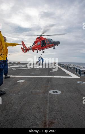 Mitglieder der Küstenwache an Bord des USCGC Stratton (WMSL 752) führen vertikale Nachschuboperationen mit einem MH-65E Dolphin-Hubschrauber im Pazifischen Ozean durch, 2. Januar 2021. Die Crew von Stratton führte Flugoperationen durch, um die operativen Fähigkeiten aufrechtzuerhalten und die Bereitschaft zu erhöhen. (USA Foto der Küstenwache des U.S. Marine Corps Sgt. Sarah Stegall) Stockfoto