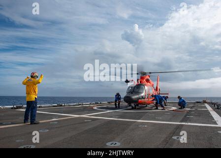 Crew-Mitglieder der Küstenwache an Bord des USCGC Stratton (WMSL 752) führen Verzurrungsoperationen mit einem MH-65 Dolphin-Hubschrauber im Pazifischen Ozean durch, 2. Januar 2022. Die Crew von Stratton führte Flugoperationen durch, um die operativen Fähigkeiten aufrechtzuerhalten und die Bereitschaft zu erhöhen. (USA Foto der Küstenwache des U.S. Marine Corps Sgt. Sarah Stegall) Stockfoto