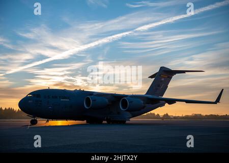 Die Sonne geht über einem C-17 Globemaster III auf der Fluglinie auf dem Yokota Air Base, Japan, auf, bevor sie am 27. Januar 2022 zur Unterstützung von Cope North 2022 mit Fracht beladen wird. Cope North 2022 ist ein jährliches gemeinsames multilaterales Training der US Pacific Air Forces, das sich auf die Koordinierung von Flugtaktiken, -Techniken und -Verfahren zur Verbesserung der Sicherheit und Stabilität in der Indo-Pazifik-Region konzentriert. (USA Foto der Luftwaffe von Staff Sgt. Braden Anderson) Stockfoto