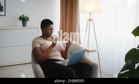 Überlastung. Junge afroamerikanische Dame, die an müden Augen leidet, die Brille auszieht und sich von der Arbeit am Laptop erschöpft fühlt Stockfoto