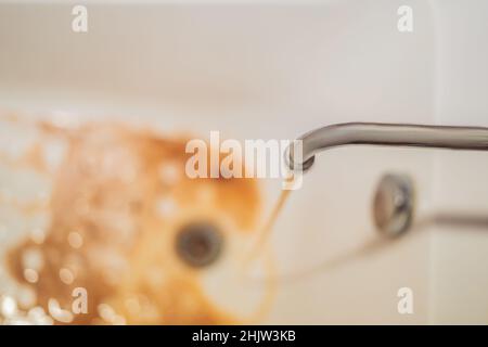 Schmutziges Braun läuft das Wasser fällt in ein weißes Waschbecken aus tippen. Umweltverschmutzung Konzept Stockfoto