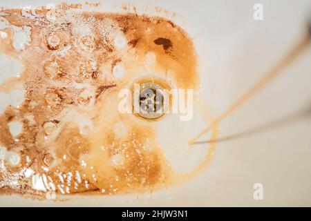 Schmutziges Braun läuft das Wasser fällt in ein weißes Waschbecken aus tippen. Umweltverschmutzung Konzept Stockfoto