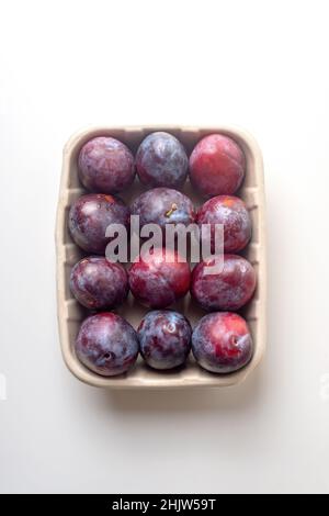 Bio-Zuckerpflaumen in ökologischen Papierverpackungen auf hellem Hintergrund.Ökologie, nachhaltig, biologisch. Stockfoto