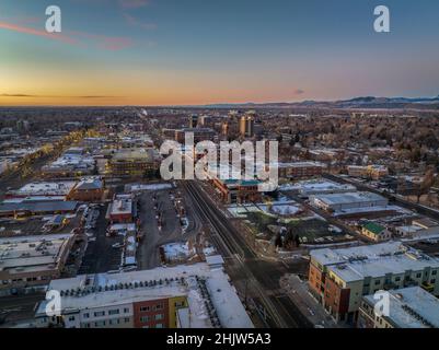 Wintersonnengang über Fort Collins, Colorado und den Rocky Mountains - Luftaufnahme der Innenstadt mit Weihnachtsbeleuchtung Stockfoto