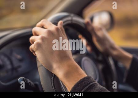 Die Hände des Fahrers am Lenkrad im Inneren eines Autos Stockfoto