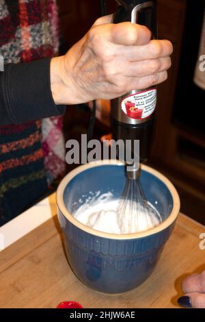 Mit einem elektrischen Stabmixer aus Edelstahl Eiweiß für gebackenes Alaska aufrühren. St. Paul Minnesota, USA Stockfoto