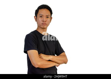 Ein asiatischer Mann trägt ein schwarzes T-Shirt mit gekreuzten Armen auf weißem Hintergrund. Stockfoto