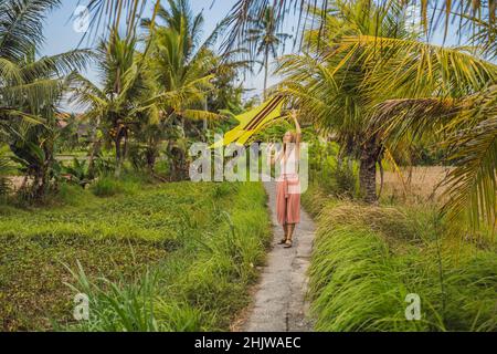 Junge Frau startet einen Drachen in einem Reisfeld in Ubud, Bali, Indonesien Stockfoto