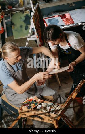 Kreative Gruppe Workshop der Malerei auf großer Leinwand im Studio. Studenten malen bei Kunstunterricht. Kunstvermittlung für Erwachsene. Hobby und Arbeit Stockfoto