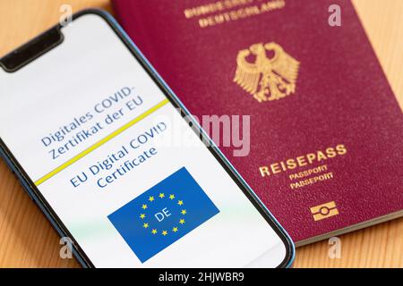 Berlin, Deutschland. 31st Januar 2022. Ein digitales COVID-Zertifikat aus der EU (l), gesehen auf einem Smartphone, liegt auf einem Tisch neben einem deutschen Pass. Wer ab Februar 1 in die EU reisen will, muss sich auf strengere Regeln vorbereiten. Die Gültigkeit der EU-Impfbescheinigungen erlischt automatisch neun Monate nach der grundlegenden Immunisierung. Um weiterhin leichter reisen zu können, muss eine Auffrischimpfung stattgefunden haben. Quelle: Fernando Gutierrez-Juarez/dpa-Zentralbild/dpa/Alamy Live News Stockfoto