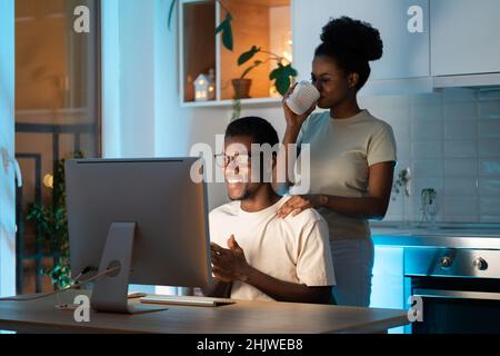 Glückliches afrikanisches Paar arbeitet am Startup-Projekt im Home Office spät, bauen familiengeführtes Online-Geschäft auf Stockfoto