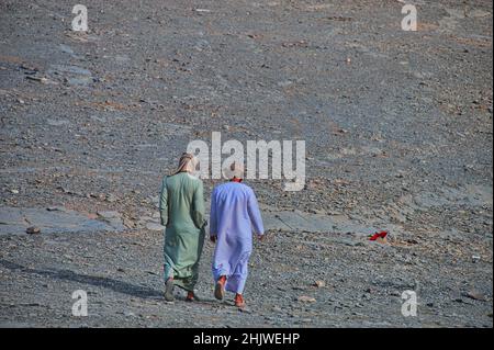 Zwei Männer in arabischer Kleidung, die in der Wüste spazieren Stockfoto