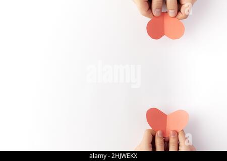 Am Valentinstag werden rote Herzen aus Papier in den Händen eines verliebten Paares gehalten. Draufsicht. Speicherplatz kopieren. Für Text platzieren. Stockfoto