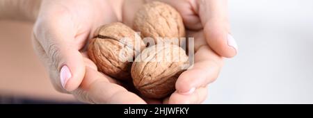 Drei reife Walnüsse in weiblichen Händen in Nahaufnahme Stockfoto