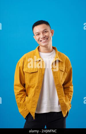 Studioporträt eines lächelnden jungen Mannes in einer weißen Senfjacke mit T-Shirt und Blick auf die Kamera Stockfoto