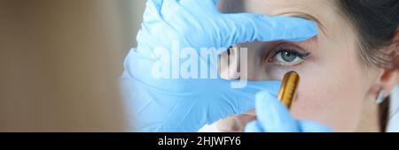 Der Arzt strahlt Licht in das Auge des Patienten, um die Pupille aus der Nähe zu überprüfen Stockfoto