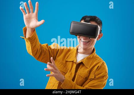 Porträt eines lächelnden jungen Mannes, der die verspielte Realität genießt und ein Videospiel spielt Stockfoto
