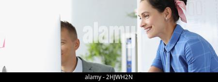 Lächelnder Mann und Frau diskutieren am Arbeitstisch über Geschäftsprozesse Stockfoto