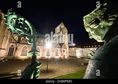 Hildesheim, Deutschland. 01st. Februar 2022. Das Bernward-Denkmal, eine Bronzestatue des Bischofs Bernward von Hildesheim, steht im Domhof vor dem beleuchteten Hildesheimer Dom. Quelle: Julian Stratenschulte/dpa/Alamy Live News Stockfoto