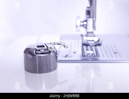 Der Arbeitsteil der Nähmaschine. Der Fokus liegt auf dem Metall-Shuttle. Foto in Pastellfarben. Nähmaschinenreparaturkonzept. Stockfoto