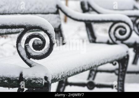 Alte Vintage Bank in einem Park im Winter vom Schnee bedeckt, Nahaufnahme Stockfoto