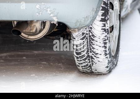 Nahaufnahme des Winterreifens eines Autos auf der von Schnee und Eis bedeckten Straße bei extrem kalten Temperaturen Stockfoto