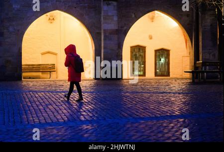 Hildesheim, Deutschland. 01st. Februar 2022. Eine Frau geht am frühen Morgen vor den Bögen des Rathauses über den Marktplatz. Quelle: Julian Stratenschulte/dpa/Alamy Live News Stockfoto