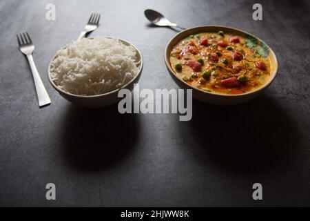Indisches Mittagsmenü gedämpfter Reis und gelbes Dal oder Hülsenfrüchte auf einem Hintergrund. Nahaufnahme, selektiver Fokus. Stockfoto