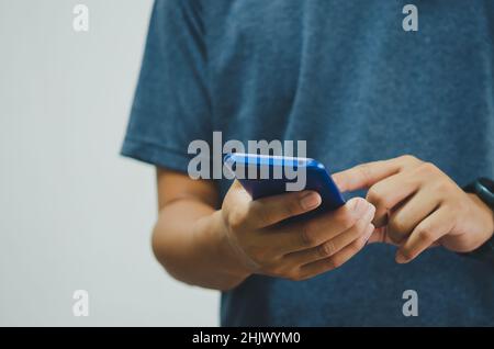 Mann in einem blauen Hemd drückt ein Mobiltelefon auf den Hintergrund. Platz kopieren Stockfoto