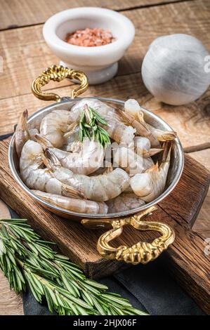 Weiße Tigergarnelen, rohe Garnelen in einer Pfanne mit Rosmarin. Holzhintergrund. Draufsicht Stockfoto