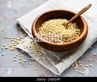 Roh Couscous in einer Holzschüssel und Löffel auf der Tabelle Stockfoto