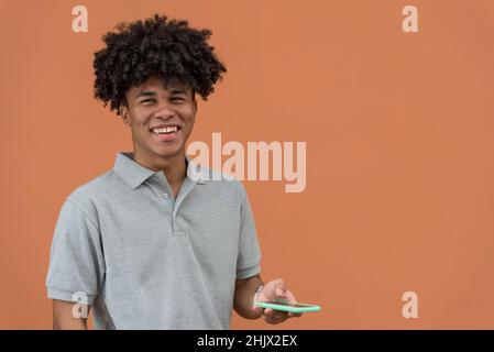 Porträt eines jungen Afro-amerikaners, der lächelt und auf sein Telefon schaut Stockfoto