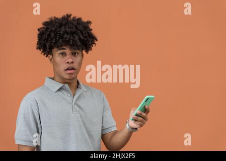 Überrascht afroamerikanischer Mann, der sein Mobiltelefon ansah, Panama, Mittelamerika. Stockfoto