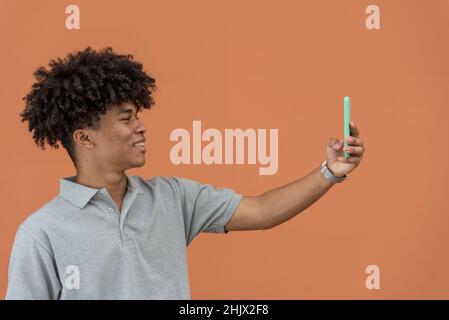 Porträt eines jungen Afro-amerikaners, der lächelt und ein Selfie an seinem Telefon nimmt Stockfoto